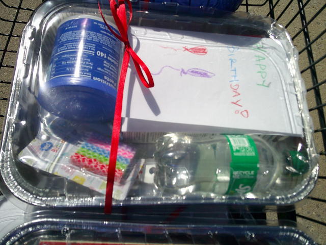 Birthday card, frosting, candles, cake mix, and sprite in foil pan.